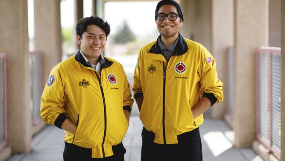two AmeriCorps members standing together and smiling in an outdoor hallway