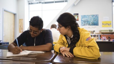 AmeriCorps member in yellow jacket watched student complete assignment,