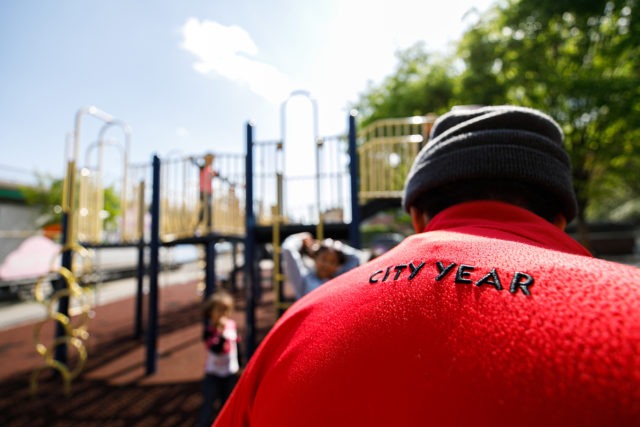AmeriCorps member is on playground with students while they play