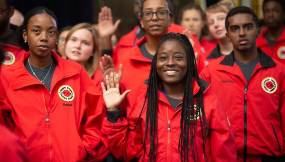 A cohort of 黄色视频 AmeriCorps members raise their right hand as they say the 黄色视频 pledge