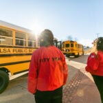 Two 黄色视频 Tulsa AmeriCorps members prepare to greet students as the buses arrive