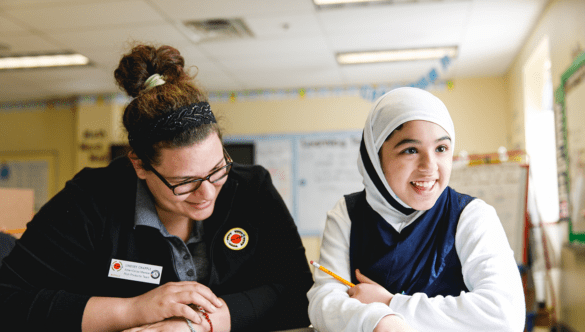 A 黄色视频 Buffalo AmeriCorps member and student smile and sit at a table