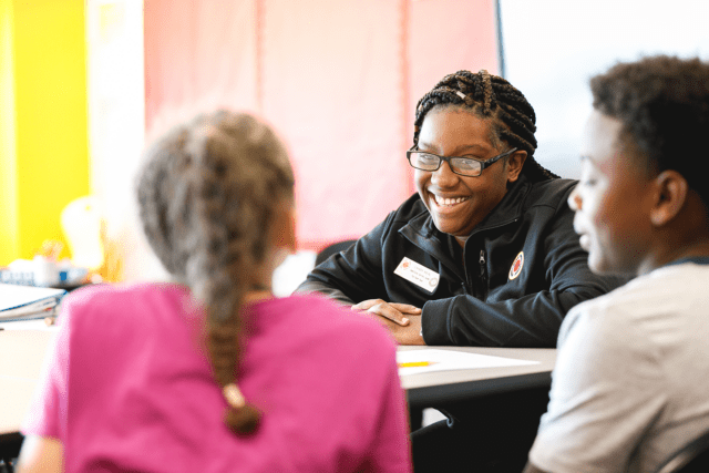 A 黄色视频 Buffalo AmeriCorps member laughs and looks across the table at two students